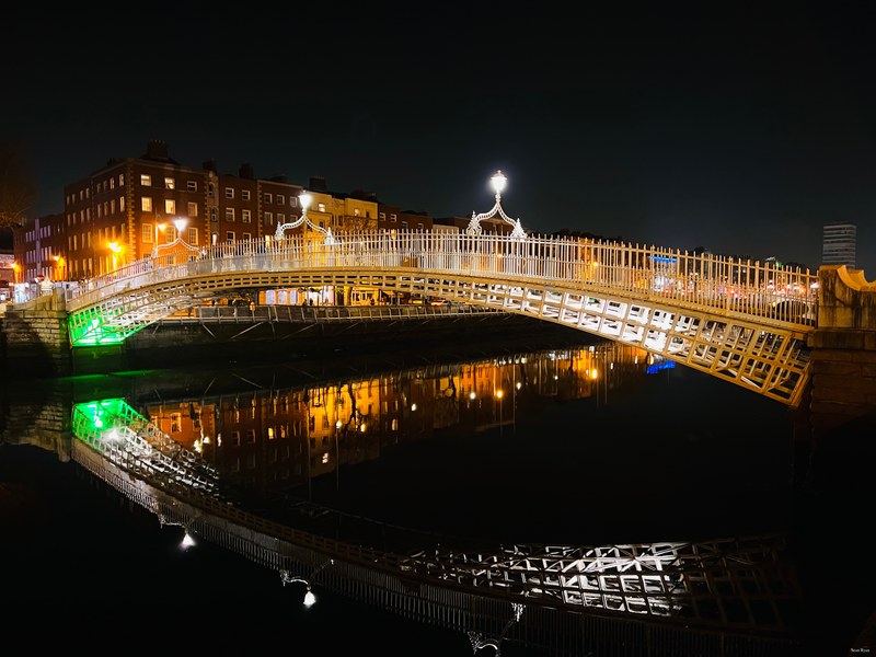 Ha’penny bridge reflected in the waters of the river Liffey by night, in Dublin